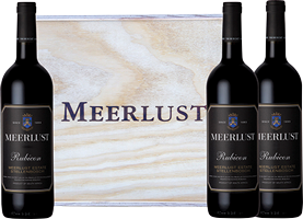 Drei Flaschen Rotwein stehen vor einer Verpackung mit dem Aufdruck -MEERLUST-. Die Flaschen sind dunkel und elegant gestaltet, während die Verpackung eine helle, natürliche Holzoberfläche zeigt.