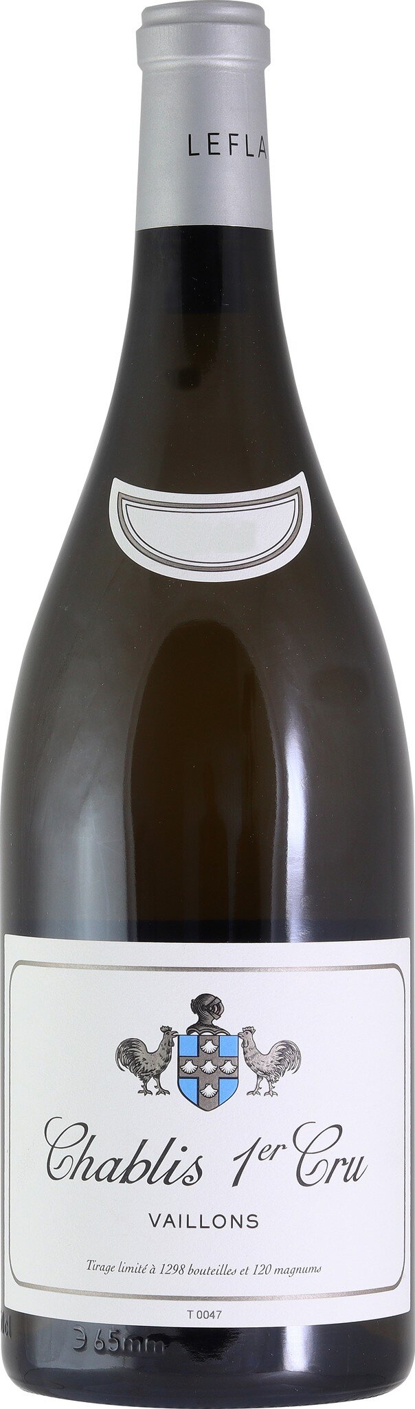 Eine Weinflasche mit einem weißen Etikett und dekorativem Schriftzug steht im Fokus. Die Flasche hat einen klassischen Korpus und einen silbernen Kapselverschluss. Der Hintergrund ist neutral.