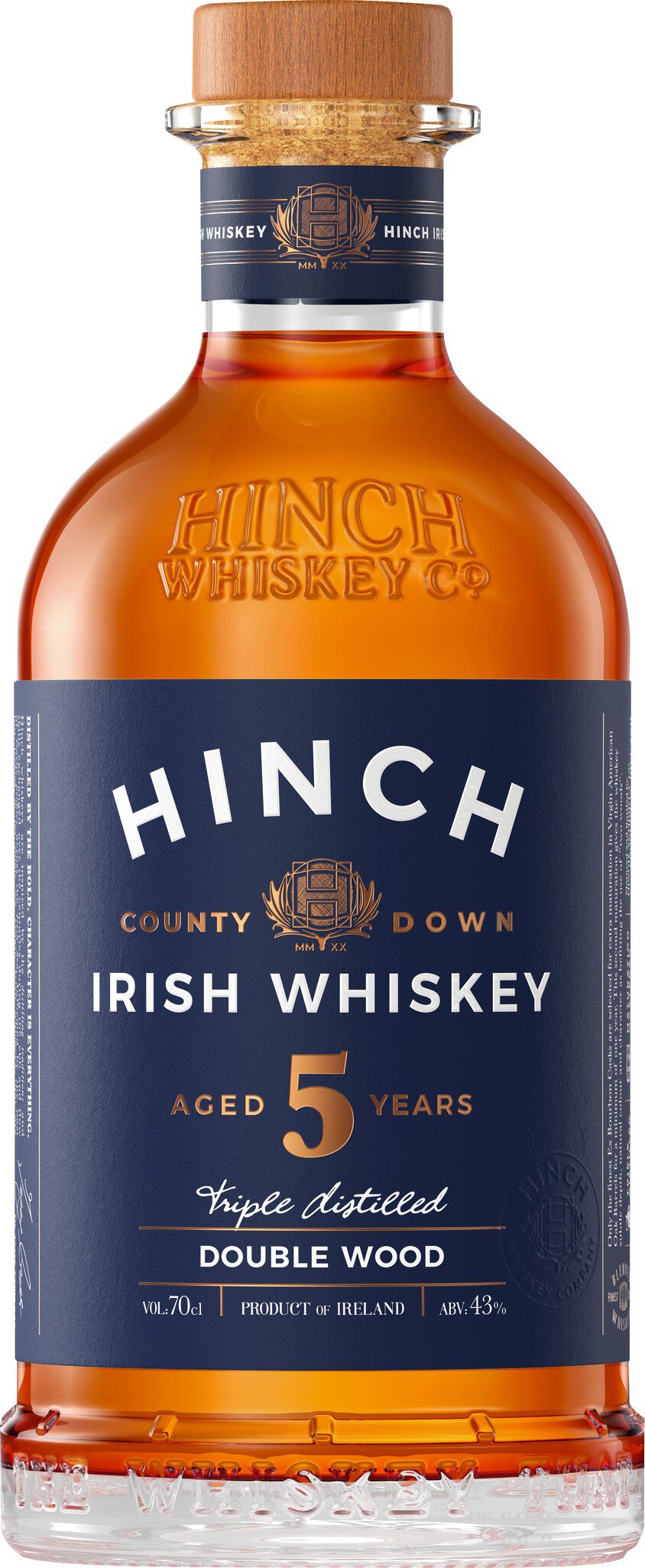 Eine Flasche Whiskey steht im Vordergrund. Sie ist bauchig mit einem goldenen Verschluss. Der Etikett zeigt den Namen -Kinch- und die Angabe -5 Jahre alt- auf einem blauen Hintergrund.