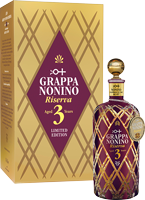 Eine elegante Flasche Grappa mit einem goldenen Etikett, die in einer gemusterten Geschenkverpackung steht. Die Flasche hat einen geschwungenen Hals und einen dekorativen Verschluss.