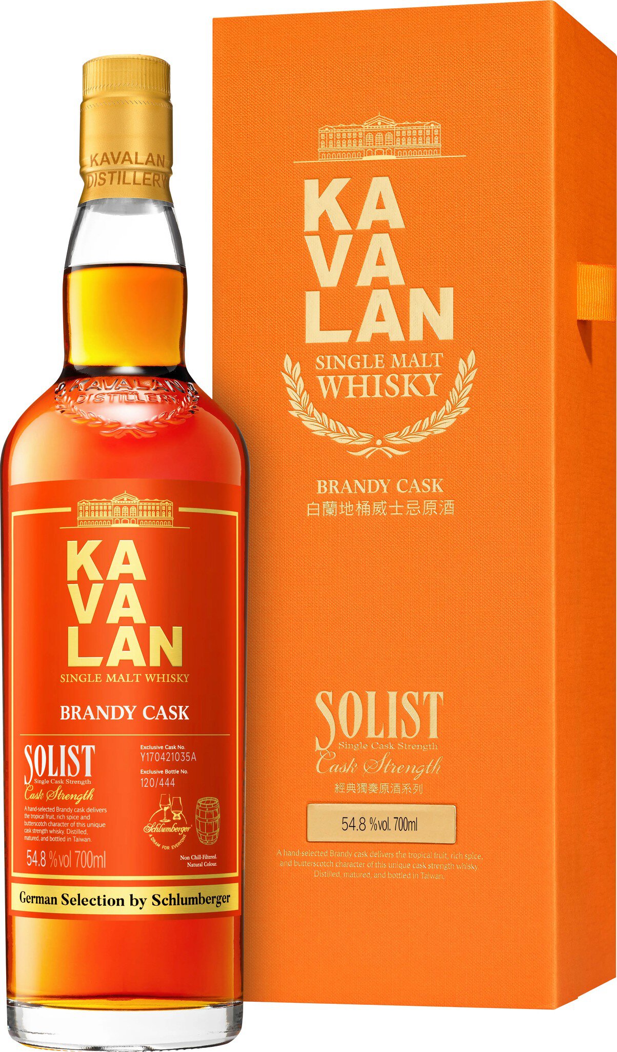 Eine Flasche mit orangefarbigem Whisky steht neben einer passenden orangefarbenen Verpackung. Die Flasche hat eine gelbe Kappe und trägt ein Etikett mit einer stilisierten Aufschrift.